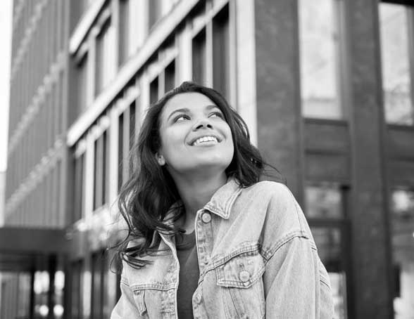 Young girl on the city streets, smiling and looking up towards the sky