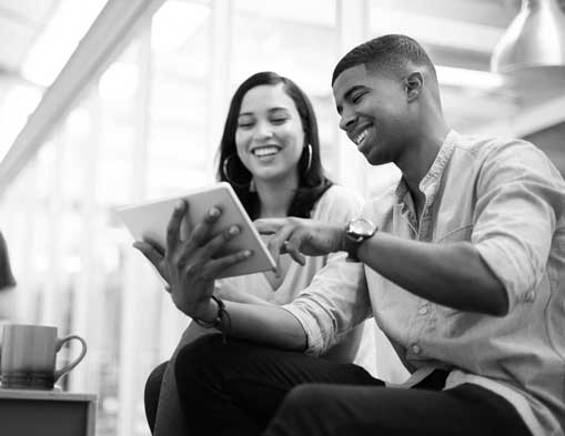 Young man shows a girl something on his iPad, they both are smiling and happy