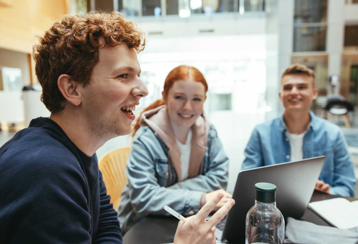 Young man is smiling and talking to his fellow high schoolers