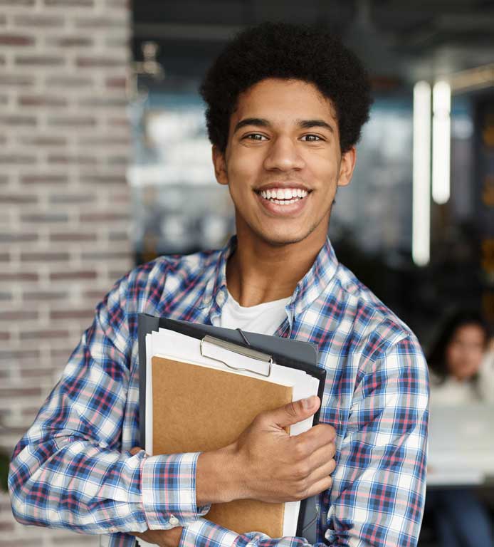 Young high school student holding his books and smiling